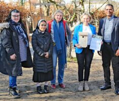 MdL Christiane Staab und Pfarrer Arul Lourdu hängen Nistkasten im KiGa auf