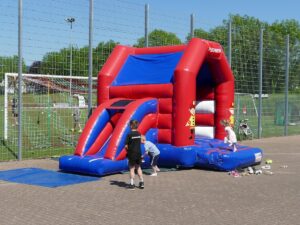 Kinder spielen auf einer rot-blauen Hüpfburg in Feuerwehr-Optik.