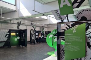 Ausstellung mit interaktiven Stationen zu Biodiversität im Zoo Heidelberg, Besucher betrachtet Exponate.