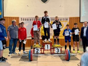 Jugendliche Gewichtheber:innen bei der Siegerehrung der Süddeutschen Mehrkampfmeisterschaften in Forst, mit Medaillen und Urkunden auf dem Podest.