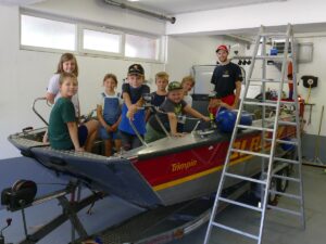 Kinder sitzen im Wasserrettungsboot „Trimpin“ mit einem Betreuer der DLRG.