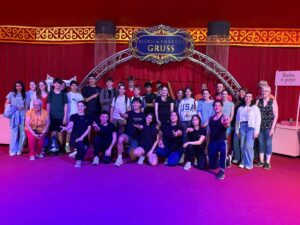 Jugendliche und Betreuer im Zirkuszelt in Tigy beim Gruppenfoto unter dem Zirkuslogo