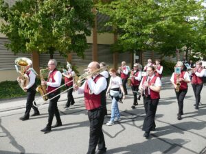 Blaskapelle mit Instrumenten und rot-weißen Westen marschiert beim Kerweumzug durch St. Ilgen.