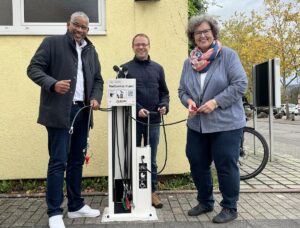 Drei Personen neben der Fahrradservicestation bei der Eröffnung an der Geschwister-Scholl-Schule.