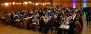 Voll besetzter Saal mit zahlreichen Gästen an langen Tischen beim Konzertabend in St. Ilgen.