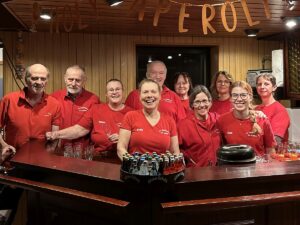 Helferinnen und Helfer des TV Germania St. Ilgen in roten Shirts hinter der Getränketheke.