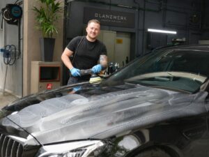 Autoaufbereiter mit Poliermaschine bei der Lackaufbereitung in einer Werkhalle von Glanzwerk.