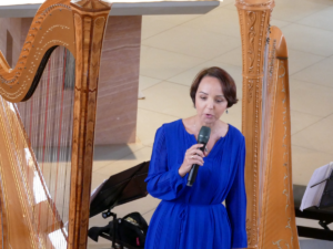 Melanie Jäger Gubelius spricht mit Mikrofon zwischen zwei Harfen in der Ägidiuskirche.