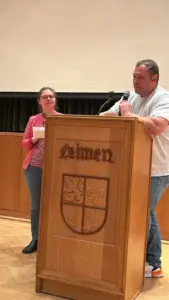 Zwei Personen am Rednerpult mit Leimener Stadtwappen im Rosensaal